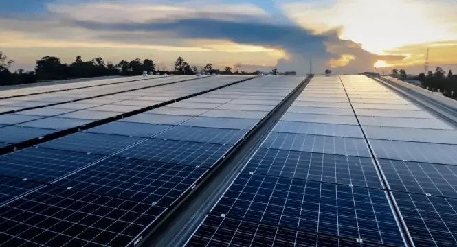 Solar panels on a large roof at sunset.